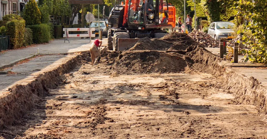 Excavator grading a street for new road base