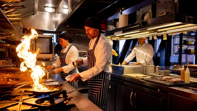 Chefs cooking over an open flame in a commercial kitchen